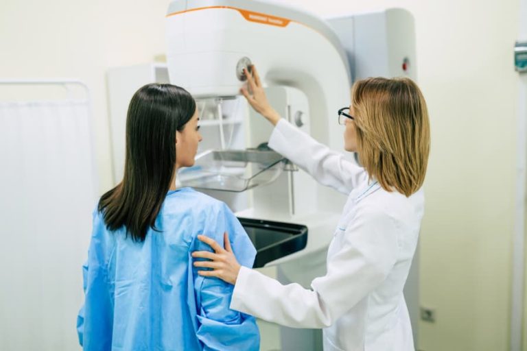 Healthcare worker helps patient prepare for a mammogram