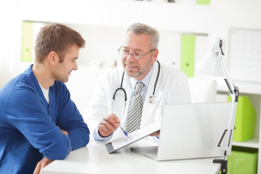 A doctor educates a patient about testicular cancer treatment options at a medical office