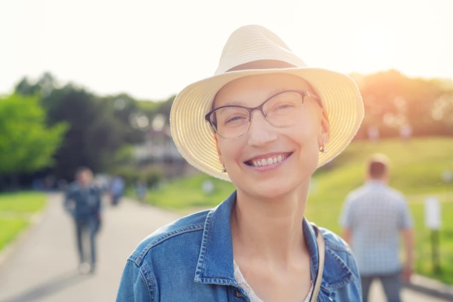 Person with hair loss from chemotherapy smiling outside on a sunny day