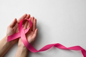 Cupped hand holding pink ribbon signifying resilience from breast cancer