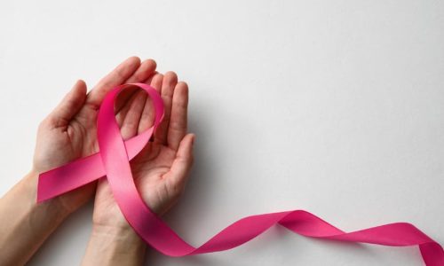 Cupped hand holding pink ribbon signifying resilience from breast cancer