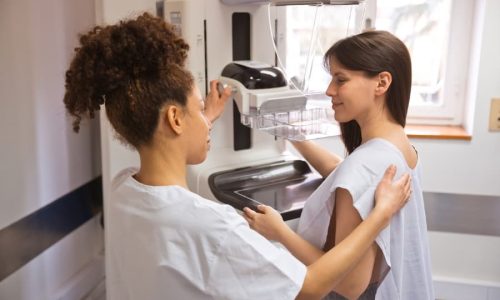 Nurse speaking with patient in gown before starting mammogram